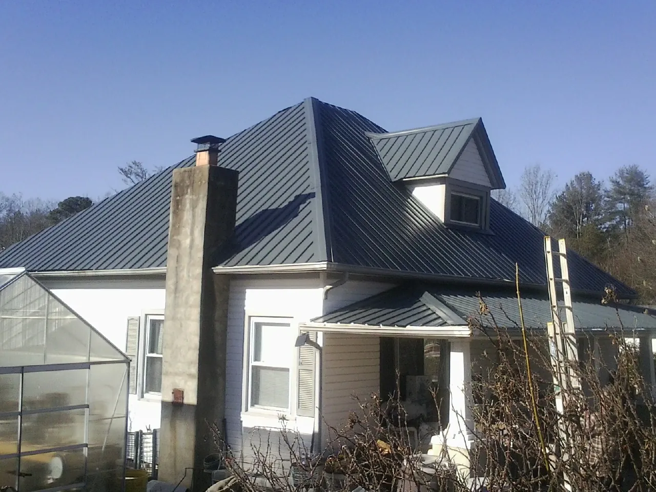 Dark blue standing seam metal roof on a white farmhouse with dormer — Slate & Tile Roof Repair by Roofing Brothers in Westerville
