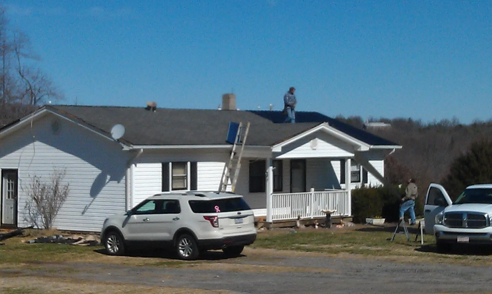 Roofers stripping shingles from a white ranch house roof in Westerville